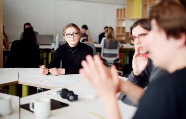 Three people around a white office table