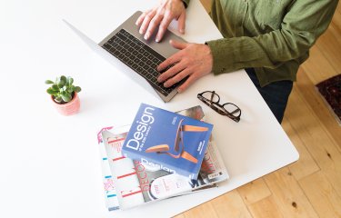 Person sat at laptop working with design book