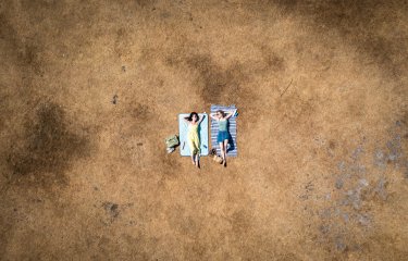 Two sunbathers lying on scorched grass 