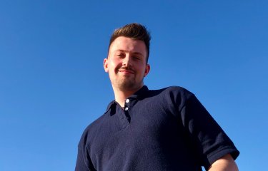 Graduate Michael Chubb smiling behind a blue sky