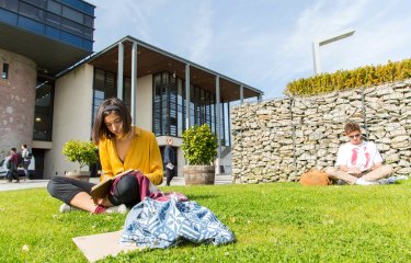 Students sit and read on the grass outside the Stannary