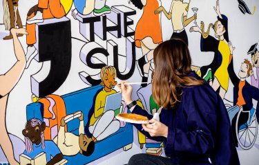 Student painting Students' Union mrual on Penryn Campus