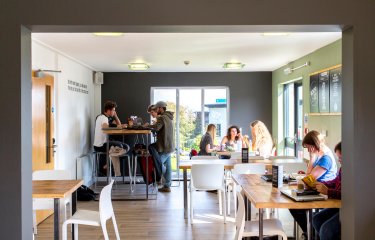 Three groups of Falmouth students sitting at tables at Koofi cafe