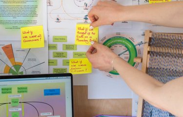 A sustainable fashion student pinning their work to a wall 