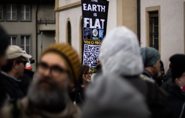 A banner raised above a crown with the text 'the earth is flat'