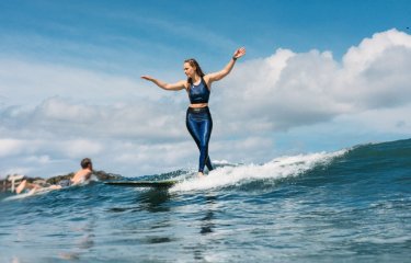 Photo of Falmouth graduate Abbi Hughes surfing on longboard in Cornwall