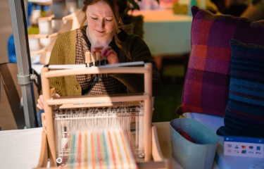 A woman sat in front of a loom