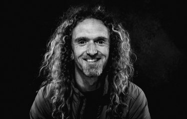 Black and white photo of a man with curly long hair