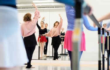 An adult ballet class posing in a studio looking at mirrors