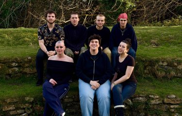 A group of people sat on steps covered in grass