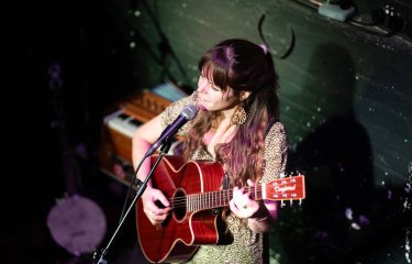 A musical performing with a guitar and singing into a microphone