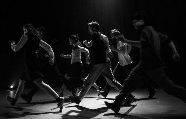 A black and white image of people dancing on stage