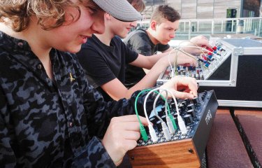 3 children in sat playing synthesisers outside