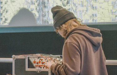 A young person stood at a audio mixing desk