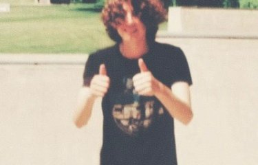 A photo of a person looking at the camera with both of their thumbs up