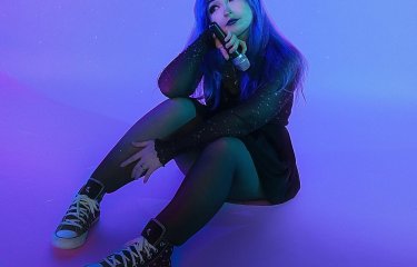 A person sat on the floor with a deep purple light on them