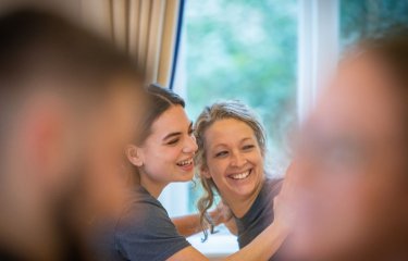 Two people in the background looking towards the camera smiling