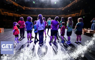 A group of young performers on the Hall for Cornwall Stage with a winter motif on the image