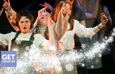 A group of young performers on the Hall for Cornwall Stage with a winter motif on the image