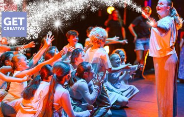 A group of young performers on the Hall for Cornwall Stage with a winter motif on the image