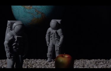 A globe with two plastic figurines and an apple in the front of the image