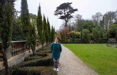 Landscape image of composer Julian Race in a garden with a large tree in the background