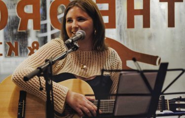 A performer playing the guitar and singing into a microphone