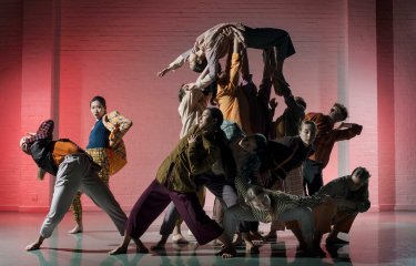 A busy image of lots of dancers moving on space looking towards the camera
