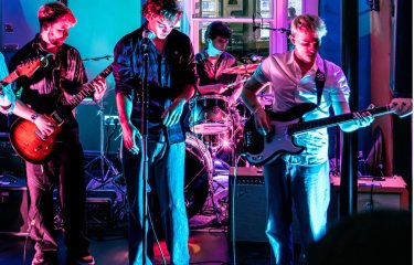 A brightly coloured image of 4 musicians performing at a local gig