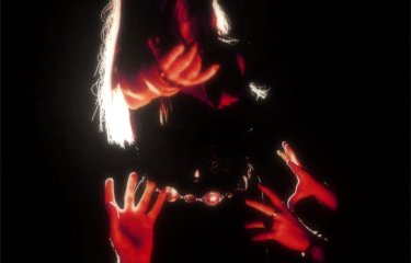 A musican in darkness with a small amount of red light on them