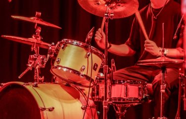 A person drumming under a orange red light