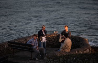 A group of musicians outside with a sea in the background