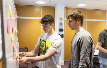 Two students mind mapping with post it notes on a white board