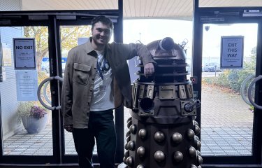 Television graduate Charles Jackson standing with Dalek in Doctor Who studios