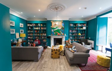 Students sat on sofa in a room full of books