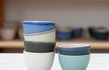 Two stacks of small ceramic bowls in white, blue and green hues.