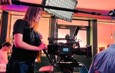 Film graduate Faith Glenister operating a camera on a film set