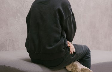 Photo of Fashion Design graduate Finlay Vincent facing away from the camera wearing black hoody with the hood up.