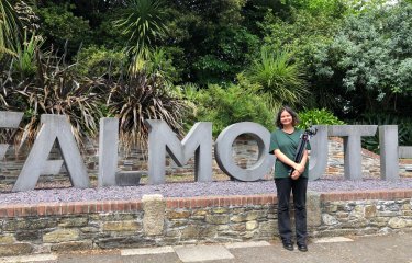 A woman stands in front of the Falmouth sign on Woodlane