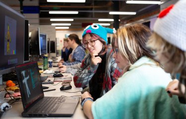 Three Falmouth University students around a computer at the 2025 Games Jam
