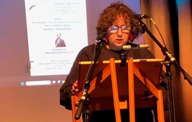 A woman stood at a pulpit reading a poem