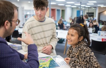 Two students speaking a staff member in The Compass