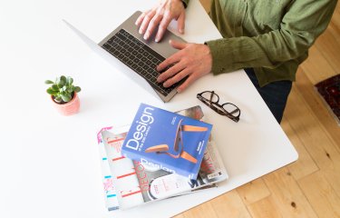 A student working at their desk with a laptop and a pile of books 