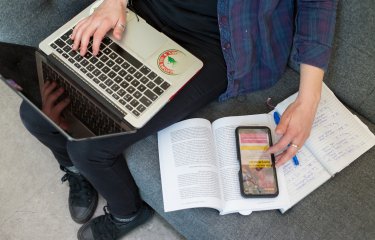 A student working on their laptop while looking at some textbooks