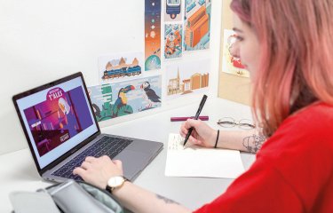 Student looking at laptop and drawing