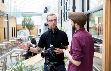 Students chatting and holding recording equipment