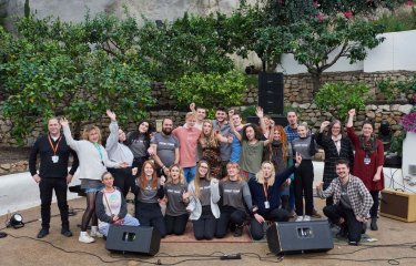 A large group of Sustainable Festival Management students posing in front of a wall with speakers on the floor