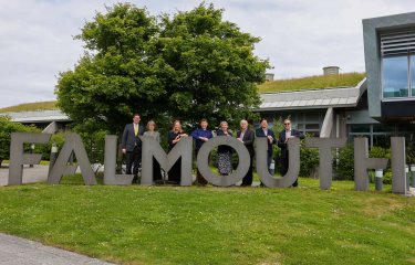 Delegates from LASALLE and Falmouth University standing behind large concrete letters reading 'FALMOUTH'