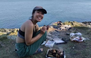 A woman in a cap smiling while crouched down on above the sea