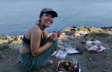 A woman in a cap smiling while crouched down on above the sea